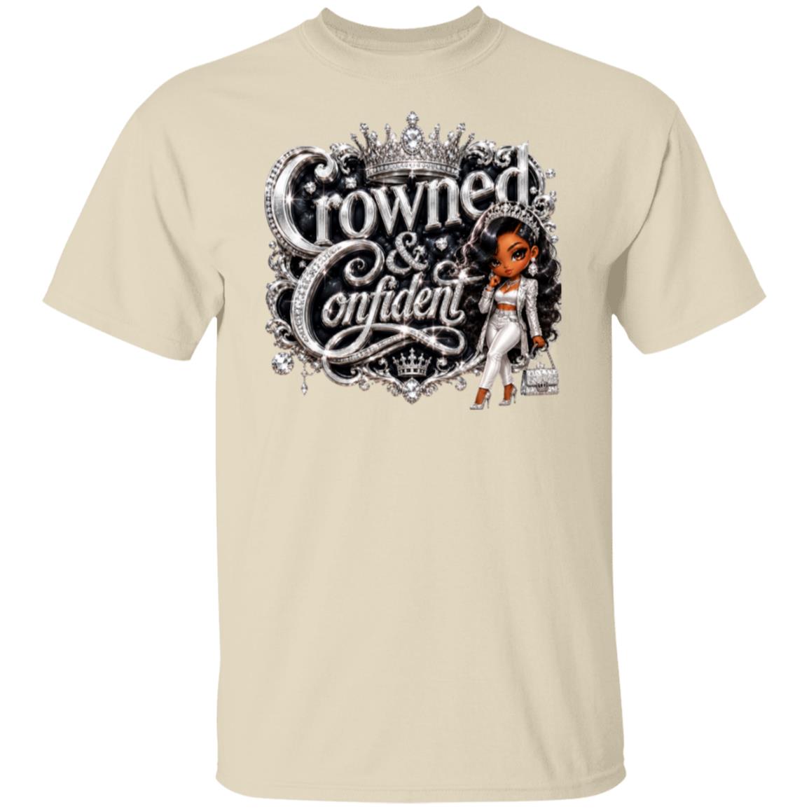 A beige short-sleeve crewneck t-shirt featuring a large graphic print on the front. The graphic displays the text 'Crowned & Confident' in a metallic silver font with a crown above, alongside an illustration of a Black woman in a white outfit holding a handbag.