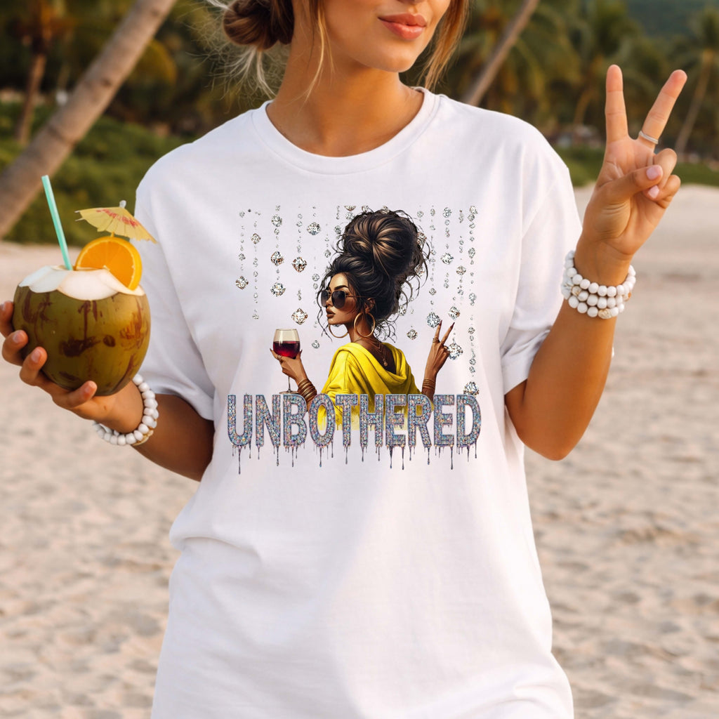 Woman on a beach wearing a white t-shirt with a graphic design and the word 'UNBOtherED'.