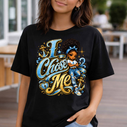 A woman wearing a black graphic t-shirt with a colorful illustration of a girl and the text 'I Chose Me' in blue and gold script, set against a blurred outdoor background.