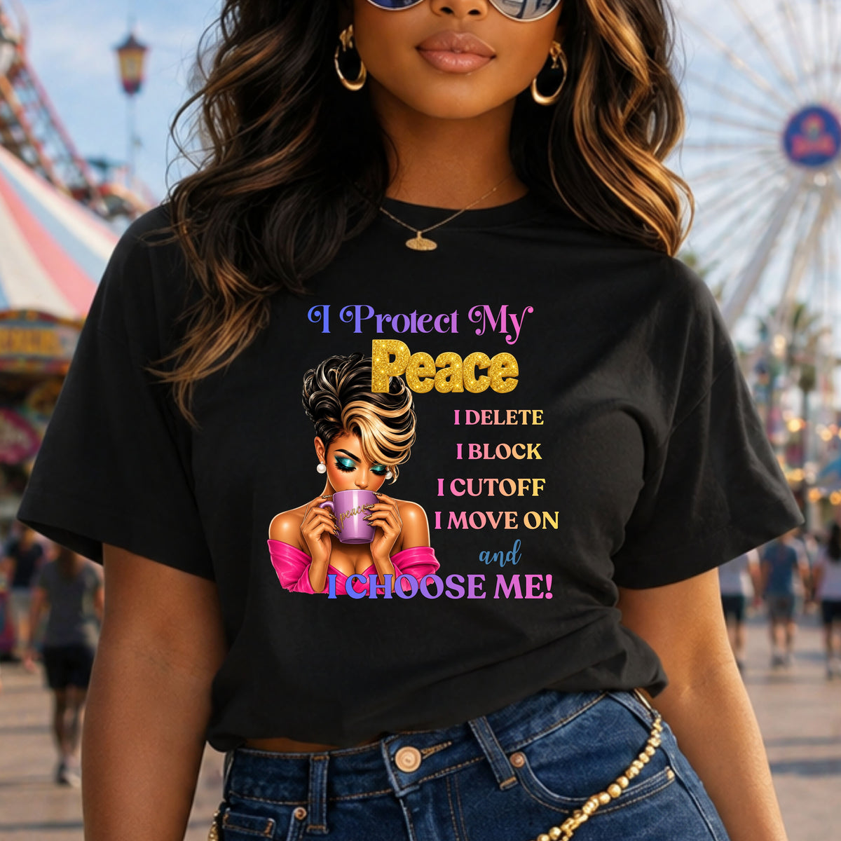 A woman wearing a black graphic t-shirt with a bold text design and an illustration of a woman holding a purple drink. The background shows a blurred outdoor fairground scene with a Ferris wheel.